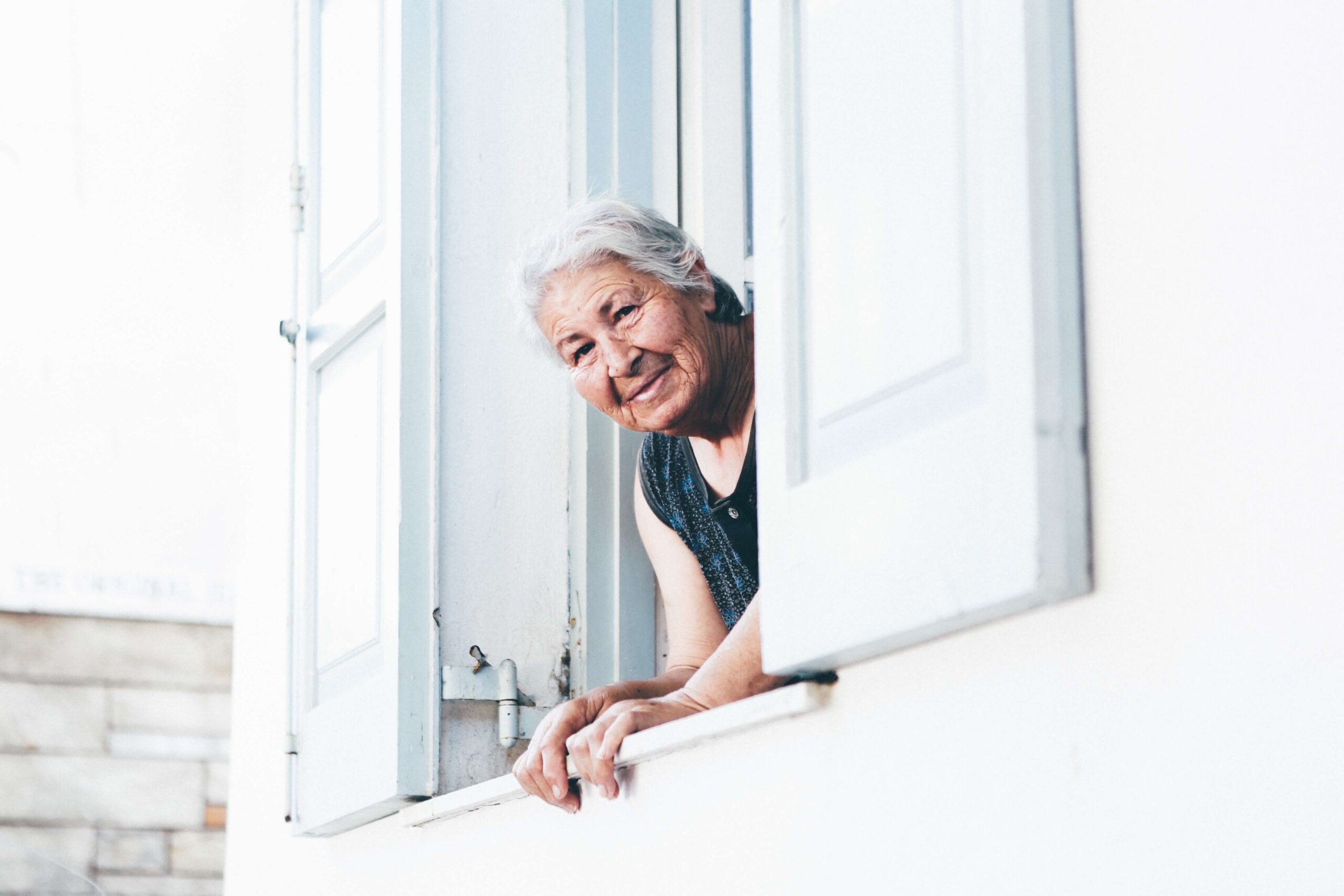 older-adult-asian-woman-peering-out-window